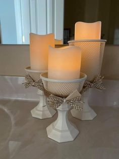 three lit candles sitting on top of a white bowl in front of a bathroom mirror