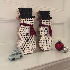 two snowmen made out of wine bottle caps sitting on top of a mantel