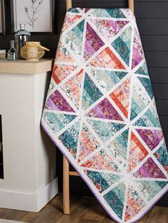 a quilted blanket sitting on top of a wooden chair next to a fire place