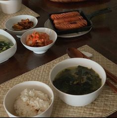 several bowls of food are sitting on a table with chopsticks and spoons