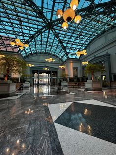 an empty lobby with glass ceiling and chandeliers