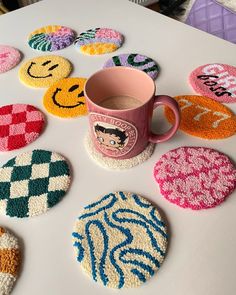 coffee cup sitting on top of a white table next to some colorful crocheted coasters