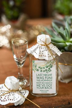 a glass jar filled with white napkins next to a wine glass and succulent plant