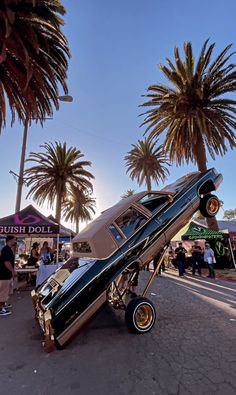 a car that is upside down on its side in the street with palm trees behind it