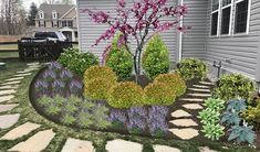 a garden with flowers and rocks in front of a house