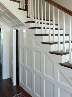 a white staircase with wooden handrails in a house