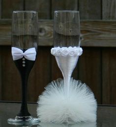 two wine glasses decorated with white flowers and feathers