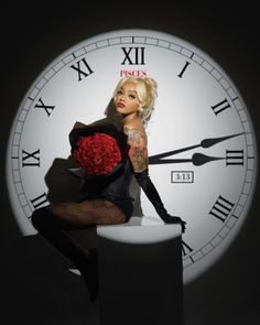 a woman sitting on top of a stool holding a bouquet of flowers in front of a large clock