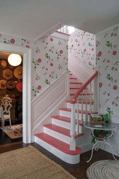 the stairs are painted pink and white with flowers all over the wall behind them, along with a rug on the floor