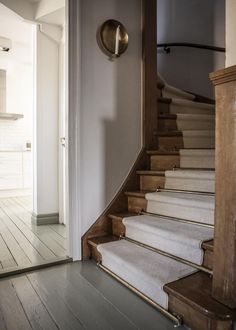 an open door leading to a hallway with white carpeted stairs and wooden handrails