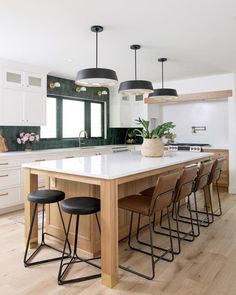 a kitchen island with four stools in front of it and lights hanging from the ceiling