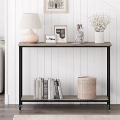 a shelf with books, vases and pictures on it next to a white wall