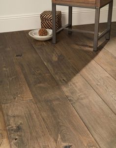 a wooden floor in a room with a chair and bowl on the ground next to it