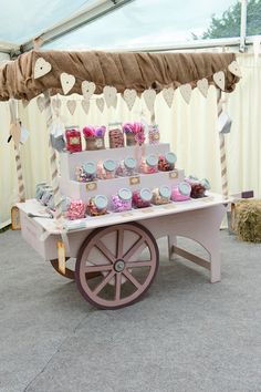 a pink cart with lots of cupcakes on it in front of a white tent