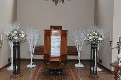 the altar is decorated with white flowers and trees in vases on either side of it