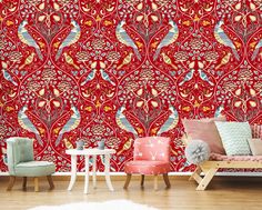 a living room with red wallpaper and colorful peacocks on the wall behind it