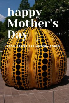 a large yellow object sitting on top of a cement ground with the words happy mother's day written above it