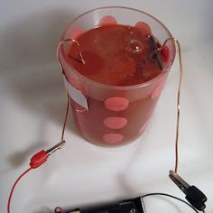 an electronic device is hooked up to a drink in a cup with red dots on it