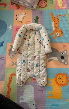 a baby's sleeping bag laying on top of a colorful mat with animals and giraffes