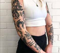 a woman with many tattoos on her arm and shoulder, standing in front of a brick wall