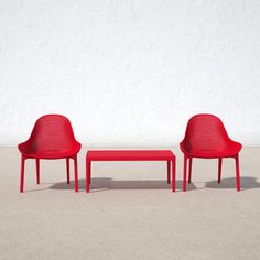 two red plastic chairs and a table against a white wall