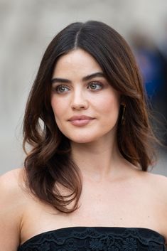 a woman with long hair wearing a strapless black dress and looking at the camera