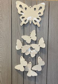 a group of white butterflies hanging from the side of a wooden wall