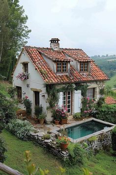 a house with a pool in front of it and lots of flowers around the windows