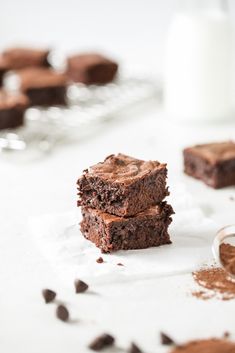 two pieces of brownie sitting on top of each other next to a glass of milk