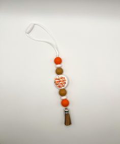 an orange and white beaded necklace with tassels on a white table top