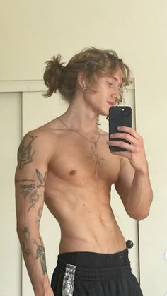 a shirtless man taking a selfie with his cell phone