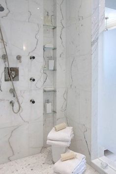 a bathroom with white marble walls and flooring, including a walk - in shower