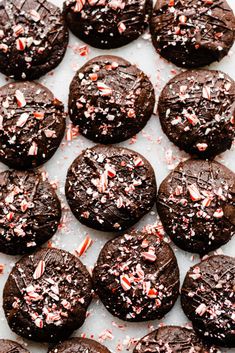 chocolate cookies with sprinkles and candy canes are on a baking sheet