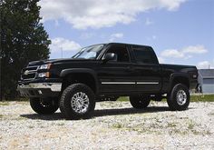 a black truck parked on top of a gravel field