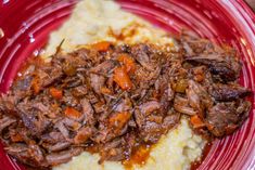 a red plate topped with meat and mashed potatoes