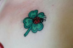 a ladybug tattoo on the back of a woman's shoulder and chest