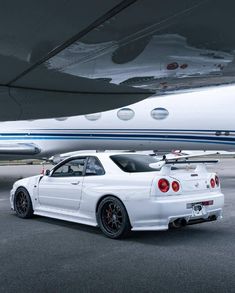 a white car parked in front of an airplane