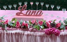 a pink table topped with lots of flowers and wine glasses next to a sign that says'lana '