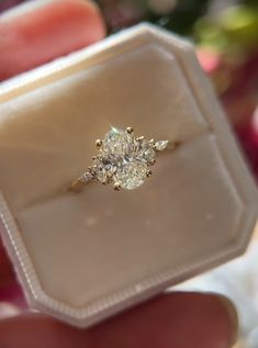 a diamond ring is being held in a white box with a christmas tree in the background