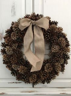 a pine cone wreath with a bow hanging on the front door's white paneled door