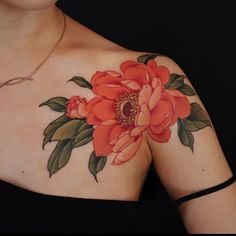 a woman's chest with an orange flower tattoo on her left arm and shoulder