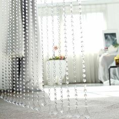 some beads hanging from the side of a curtain in a room with a couch and table