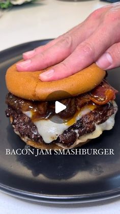 a hamburger being held up on a black plate