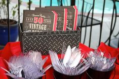 some wine glasses are sitting on a red tablecloth and there is a sign in the background