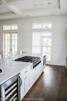 a kitchen with white cabinets and marble counter tops, along with an island in the middle