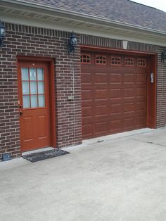 two brown garage doors in front of a brick building