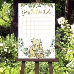 a sign with a bear on it in front of some trees and bushes that says guess the due date