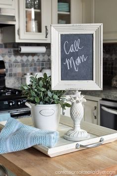 a kitchen counter with a potted plant and a chalkboard sign on it that says call mom