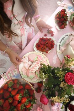 a table topped with lots of plates and bowls filled with strawberries on top of it