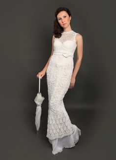 a woman in a white dress holding an umbrella and posing for the camera on a gray background